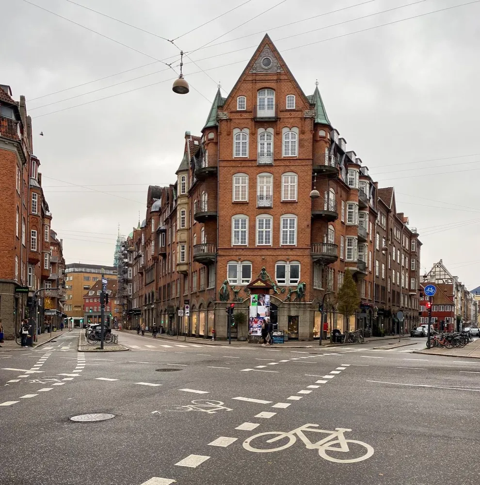 A red brick corner building with turrets above an empty crossroads