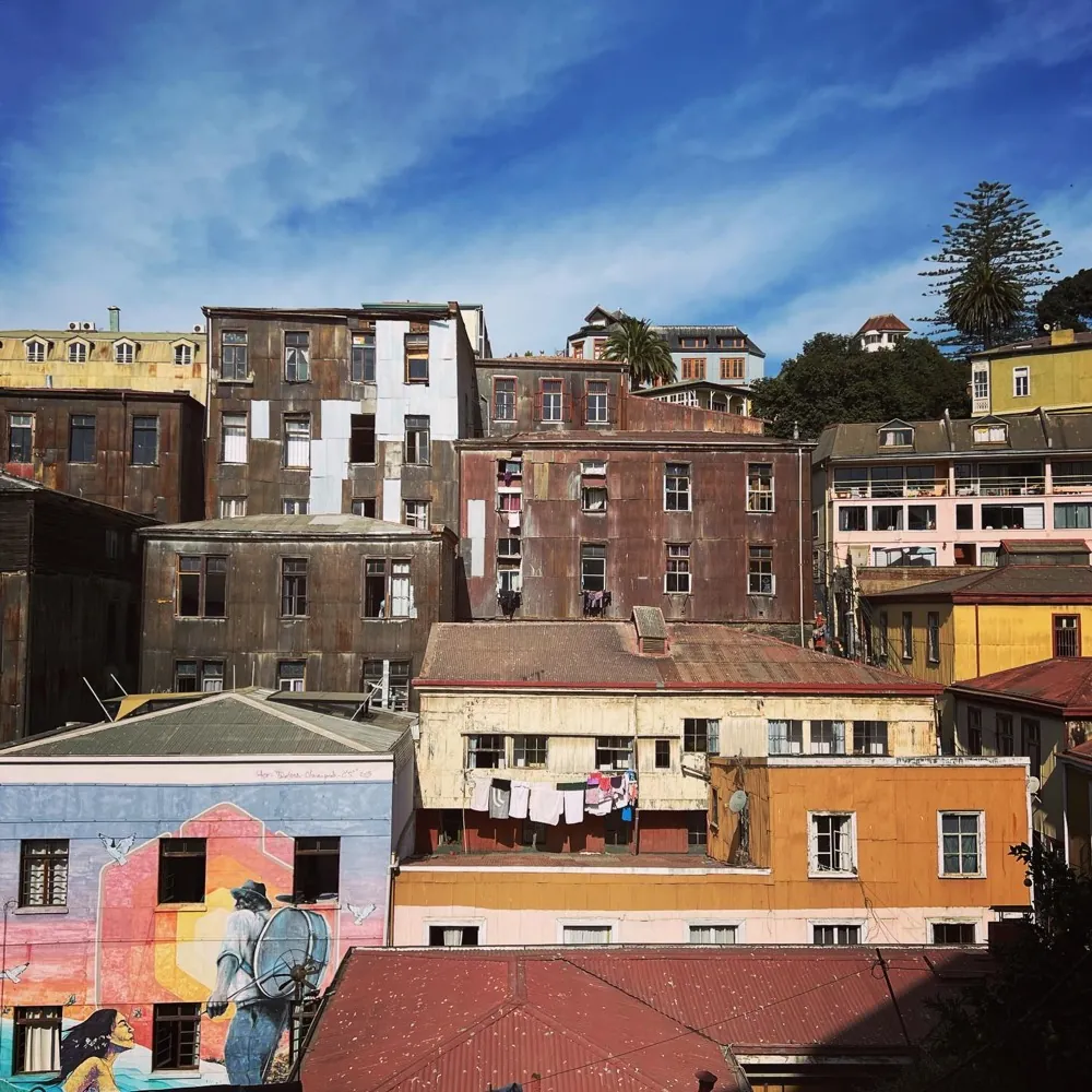 Brightly painted houses stacked up a steep hillside, with a mural across one wall