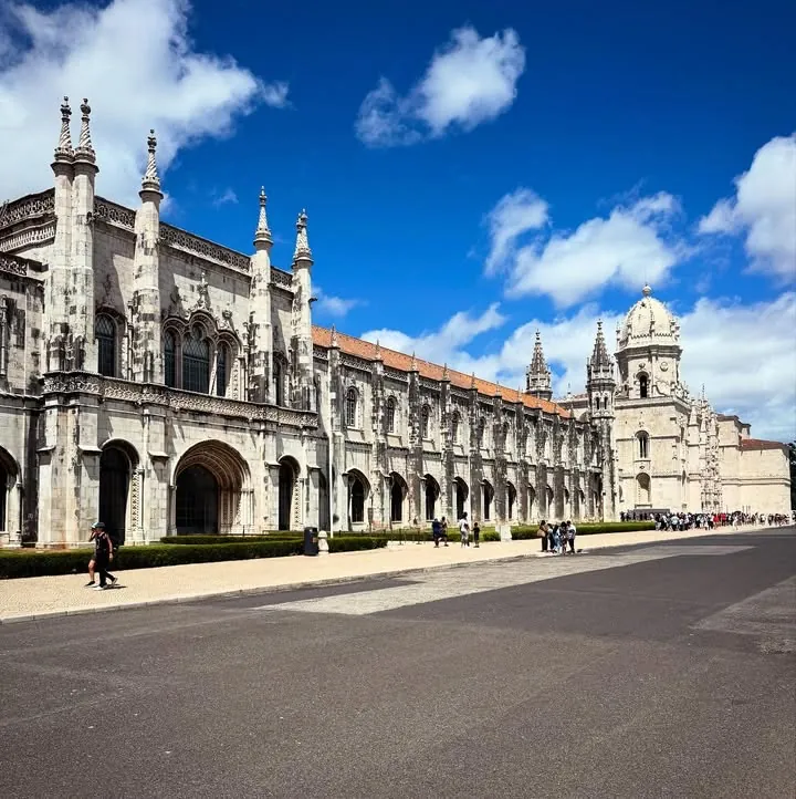 The long ornate stone facade of a monastery under a bright sky