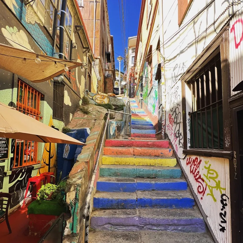 A steep alley of rainbow-painted steps between mural-covered walls