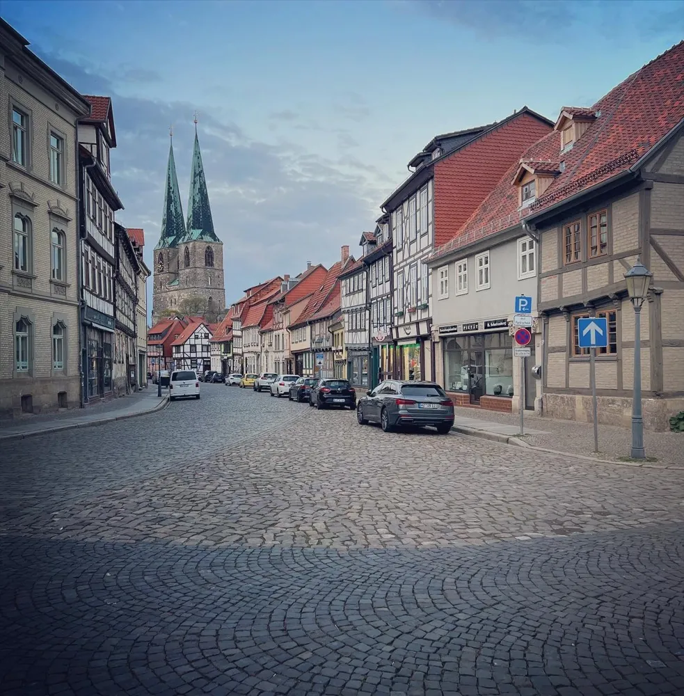 A quiet street of timber-framed houses leading to a twin-spired church
